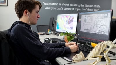 Animation students working at computer and drawing with a tablet