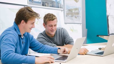 Two male students seated while looking at a laptop