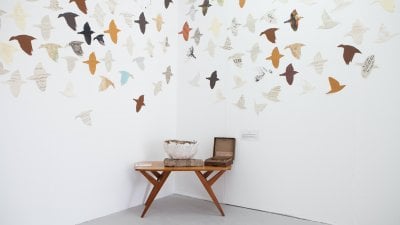 A bowl and small box on a table with cut out birds on the wall