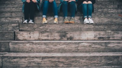 Four people sitting on steps wearing jeans and trainers