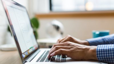 Students hands typing at a laptop.