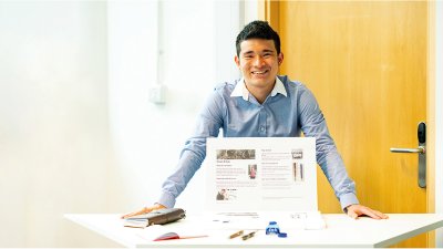 Business & Entrepreneurship student standing at a display table, smiling