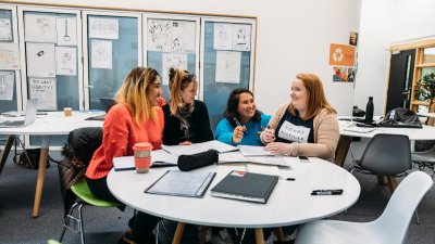 four Creative Advertising students laughing around a table