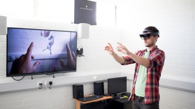 A Falmouth University student wearing a VR headset with a flat screen TV