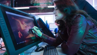 Games academy female student in black leather jacket drawing at graphic tablet