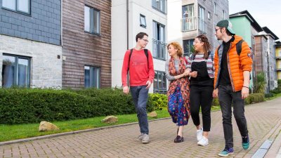 Students walking through Glasney Village with arms linked.