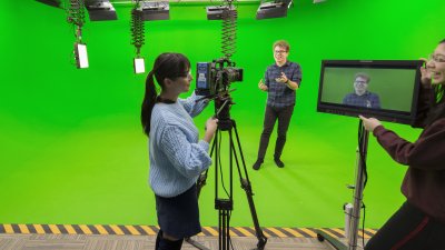 Falmouth students working camera and viewing a screen in a green studio.