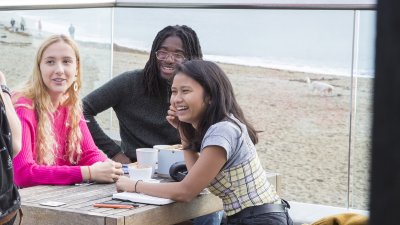 students sat outside on a bench overlooking the sea