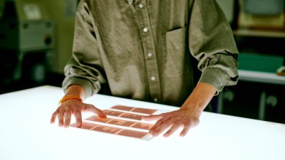 Falmouth student wearing a green shirt looking at film negatives on a light box.