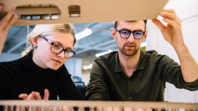 Interior design students looking inside a model.