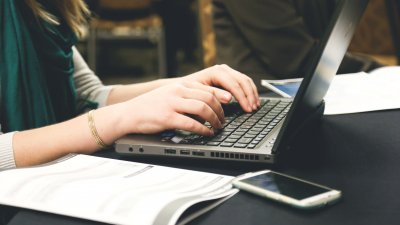 Woman studying at laptop with books and journals