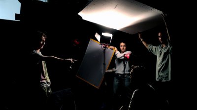 Falmouth Film students holding up reflectors in dramatically lit studio