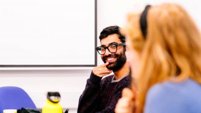 Falmouth University student with ginger hair in front of a bearded man wearing glasses and a purple jumper.