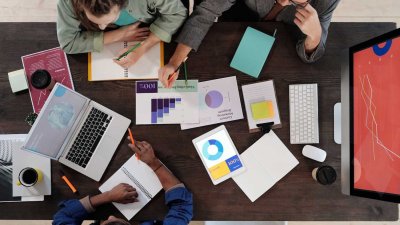 Three people sat at a table with graphs on paper
