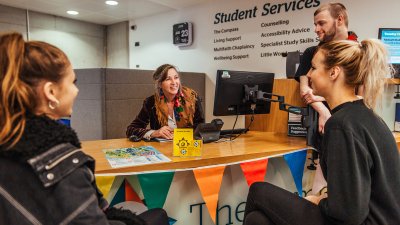 Staff and students discussing around a desk.