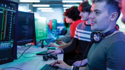 A student coding at a computer, wearing headphones