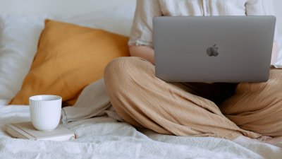 A person sat crossed legs with an apple mac and a cup