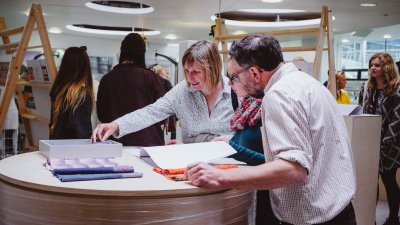 A girl with her parents looking through sketchbooks at a Falmouth University Open Day