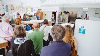 Families in the fashion and textiles studio listening to the smiling lecturer