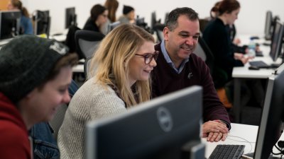 Student and lecturer working in room full of computers.