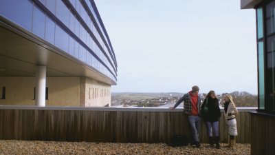 Falmouth students standing on bridge at Penryn campus with vast sky behind them