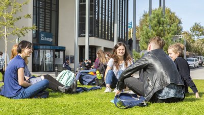 Students sitting on grass at Penryn campus.