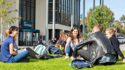 Penryn campus students outside exchange, sitting on grass