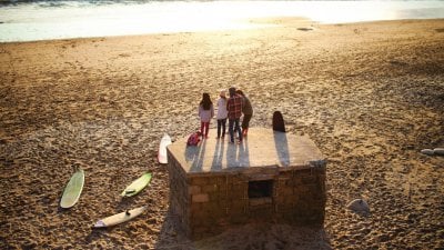 A group of students standing on a pillbox on the beach with sand and sea