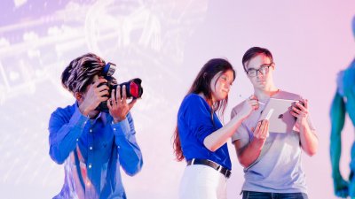 A student looking through a camera and two students looking at an iPad