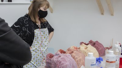 A student standing over a line of models