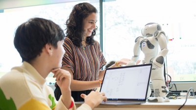 Two Robotics students operating a small robot with a laptop