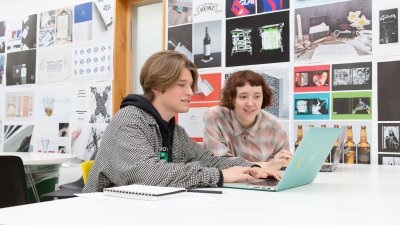 Two Falmouth University students working together at a laptop in a graphic design studio 