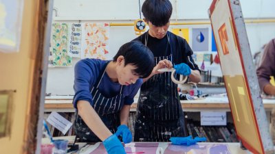 Two Falmouth University Graphic Design students screen printing in a studio