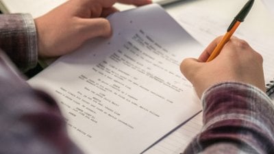 Hands holding a script and annotating it with a pen