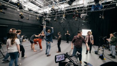 Film students combat fighting and filming in a studio.