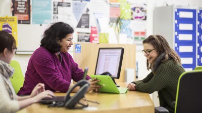 A staff member and student smiling at a desk