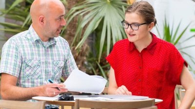 Student funding staff at a table with palm trees