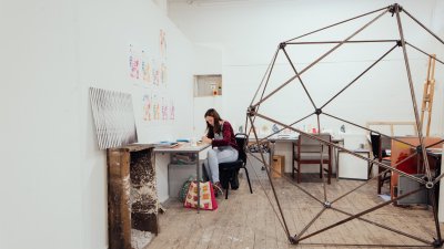 Female student in a studio with large metal sculpture