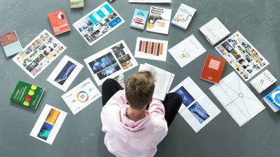 Student sitting cross legged with work laid out around him