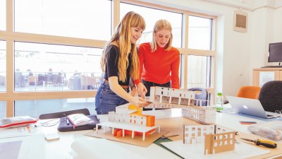 Two Interior Design students with model buildings