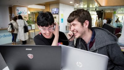 Falmouth University students listening and laughing on their headphones