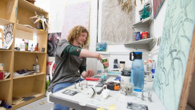 A male student with curly hair sat in a Fine Art studio at Falmouth University