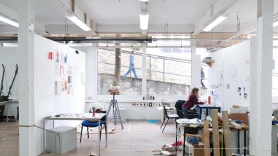 Art student working in studio with large window on Falmouth campus and person walking past and looking in.