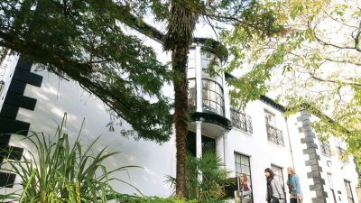 Period house on Falmouth Campus with trees and students walking by