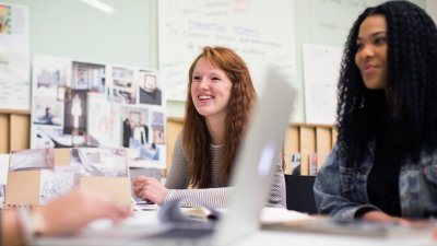 Smiling fashion marketing students working together around a desk.