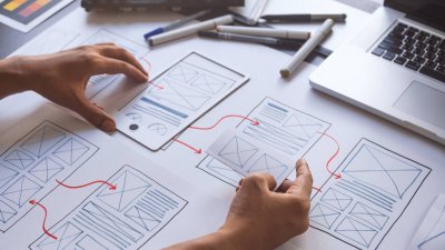 website layout plans on paper with hands and pens