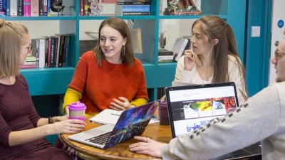 Students discussing in front of bookshelves.