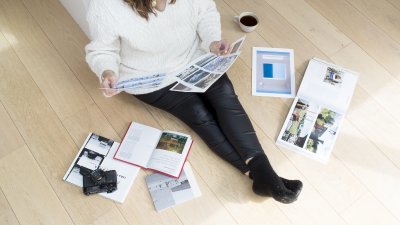 An online photography student sat on the floor with their work