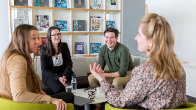 Four people (members of the Launchpad Outreach team at Falmouth University) sat around a table and smiling in the midst of conversation. 
