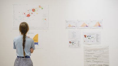 A girl looking at print outs of business graphs on a wall